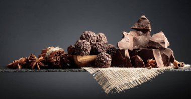 Çikolatalı trüf, kırık çikolata ve baharatlı. Çikolata, tarçın çubukları ve koyu bir arka planda anason. Boşluğu kopyala.