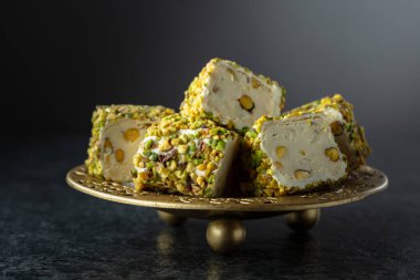 Geleneksel Türk lezzetleri, siyah arka planda altın tepside fıstıklı.