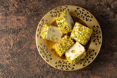 Geleneksel Türk lezzetleri, fındıklı ve altın kaplamalı, kahverengi arka planda. Üst görünüm.