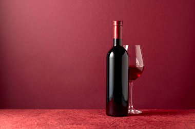 Kırmızı arka planda bir şişe kırmızı şarap. Boşluğu kopyala.