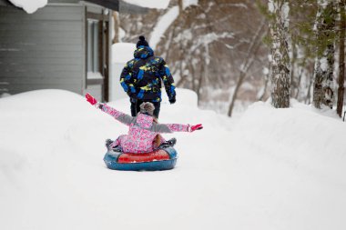 Kış eğlencesi ve eğlence konsepti. Babam bütün aileyi kar borularına bindirir. Parktaki patika boyunca..