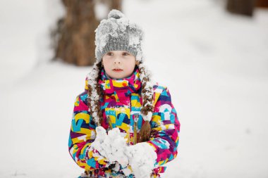 Kışın kar kaplı bir parkta örgülü gri şapkalı kız.
