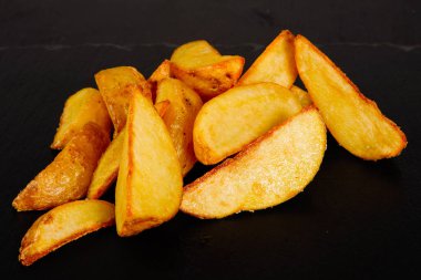 Kafeteryadaki masada siyah bir tabakta patates dilimleri.