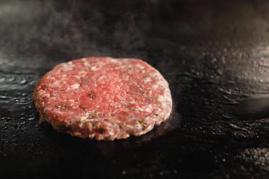 Doğranmış et pirzolası ve elektrikli ocakta dumanla kızartılıyor..