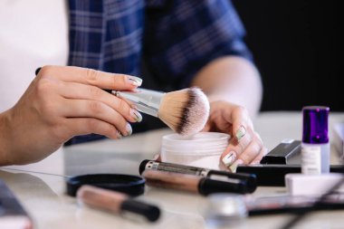 Kadınların elleri, masanın üzerine rastgele dağılmış makyajla sihirbazlık yapıyor. Yakın çekim, seçici odaklanma.