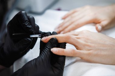 Manikürcü, bir güzellik salonundaki müşterinin tırnaklarına jöle sürmüş. Yakın plan..