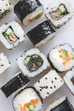 Japon suşi ruloları hazırla, beyaz arka planda susam tohumlu somon balığı. Üst görünüm.