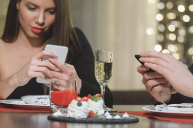 Güzel bir kadın kafedeki bir masada akıllı telefon okur..