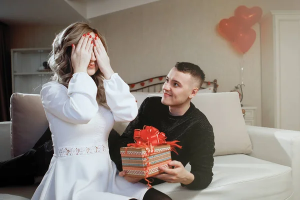 Man presents a woman a gift box in romantic interior. Birthday Celebration Concept, Just Married, Valentine\'s Day.