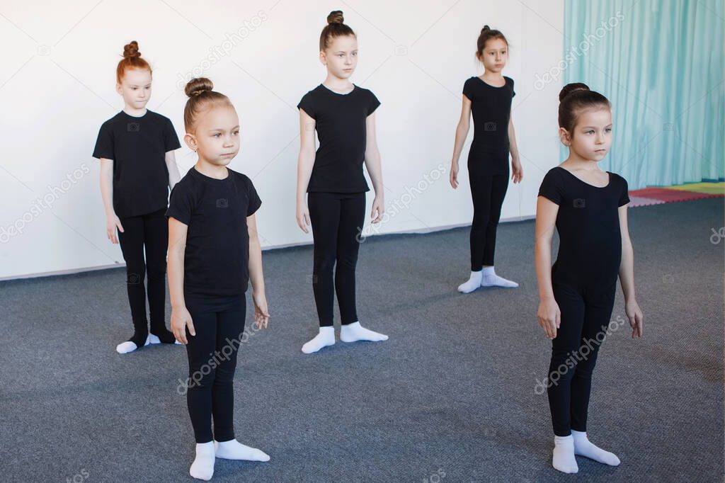 Group of teenage girls in dance, ballet, rhythmic gymnastics classes. Black leotards, hair in a bun, choreography, attentiveness, white socks.