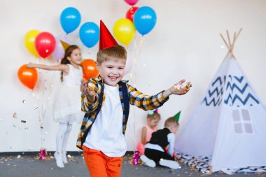 Şapkalı ve şık giysili çocuklar eğlenin ve doğum günlerinin tadını balonlarla çıkarın..