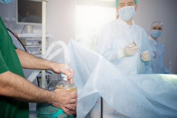 Anesthesiologist puts on a mask for inhalation anesthesia to a patient before surgery.