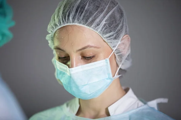 Nurse in a cap and mask during surgery