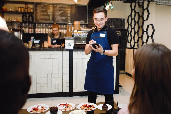 Waiter takes a customer order for a tablet with a stylus in a cafe or restaurant.