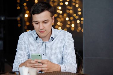 Kafedeki masada akıllı telefonu olan bir adam..