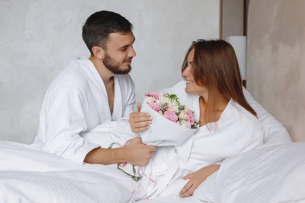 Homem Barbudo Buquê Flores Para Uma Mulher Uma Cama Branca — Fotografia de Stock