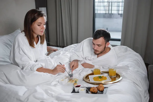 一个留着胡子的男人和一个穿着白衣的女人正在床上吃早餐 有选择的重点 — 图库照片