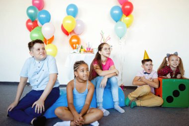 Çocuklar bir doğum günü kutlamasında toplar, şapkalar, şekerler ve kahkahalarla.