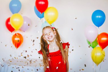 Kırmızı elbiseli, at kuyruklu ve taşaklı sarışın kız neşeyle gülüyor..