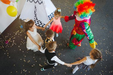 Çocuklar doğum günü partisinde bir palyaçoyla oynar ve eğlenir..