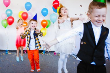 Şapkalı ve şık giysili çocuklar eğlenin ve doğum günlerinin tadını balonlarla çıkarın..