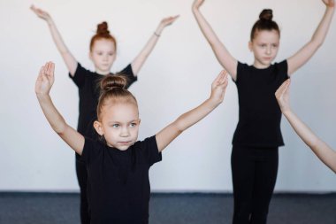 Dans, bale, ritmik jimnastik gruplarındaki genç kızlar. Siyah taytlar, topuz şeklinde saçlar, koreografi, dikkat. Seçici odak.