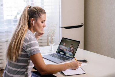 Karantina sırasında evde dizüstü bilgisayarda çalışan bir kadın. Günlüğe yazıyor. Salgın, koronavirüs salgını.