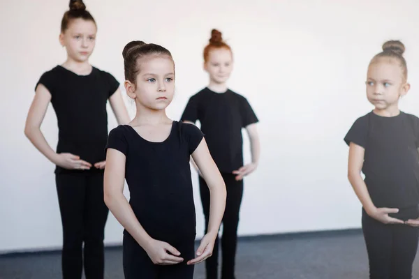 Girl teenager in group classes in dance, ballet, rhythmic gymnastics. Black leotards, hair in a bun, choreography, attentiveness, white socks.