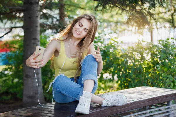 Woman Makes Selfie Smartphone Yellow Shirt Jeans Bench City Park — Stock Photo, Image