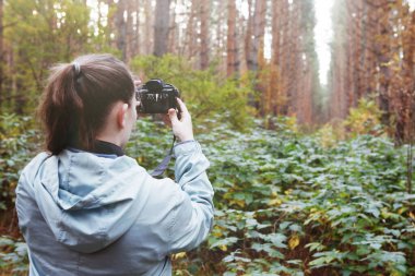 Ormanda mavi ceketli bir kadın fotoğrafçı..