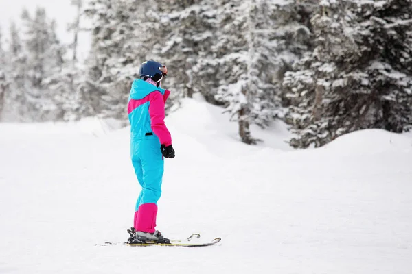 Skier is skiing on the slope of a snowy mountain in a natural resort. Ski equipment: blue pants, hard hat, warm jacket, glasses. Selective focus. — Stock Image Skier Skiing Slope Snowy Mountain Natural Resort Ski Equipment Blue Royalty Free Stock Images