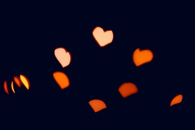 Siyah arka planda parlak sarı bulanık kalp ışıkları. İşlem sonrası fotoğraflar ve tasarım için Bokeh.