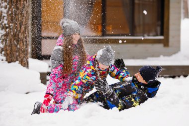 Aile annesi, babası ve kızı evin yakınındaki kış ormanında karla oynayıp eğleniyorlar..