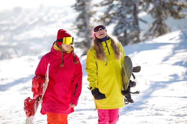 2人のスノーボーダーが歩いて雪に覆われた山で話をします 彼らはスキー服を着ています 赤と黄色のジャケット ニット帽 健康的なライフスタイル スポーツの概念 選択的焦点 — ストック写真