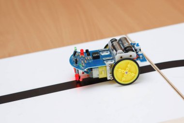 Tekerlekli bloklardan robot inşaatçıları. Siyah bir kasetle araba kullanmak. Yol dedektörüyle kendini kontrol et. Okulda robot laboratuvarı var. Robot konsepti. Fütürist bilimsel konsept. Seçici odak.