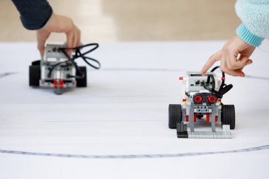 Çocukların elleri, robotları bloklardan kontrol ediyor. Okulda robot laboratuvarı var. Ev yapımı küçük robotların savaşı. Modern teknolojiler. Robot konsepti. Fütürist Bilim Konsepti. Seçici odak.