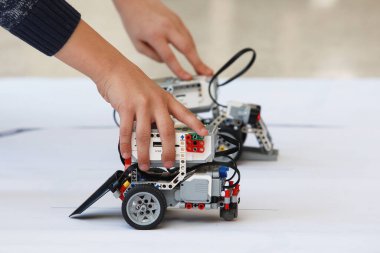 Çocukların elleri, robotları bloklardan kontrol ediyor. Okulda robot laboratuvarı var. Ev yapımı küçük robotların savaşı. Modern teknolojiler. Robot konsepti. Fütürist Bilim Konsepti. Seçici odak.