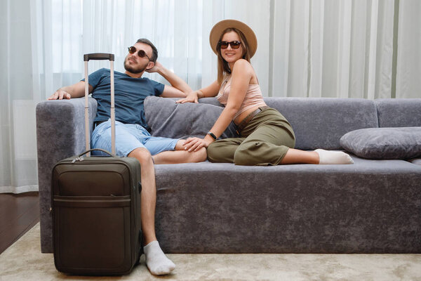 Two lovers in sunglasses and hats are having fun on the sofa. Rest at the hotel, travel tourists.