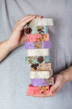 Kadın eli bir yığın ev yapımı sabun tutuyor. Küçük işletmeler, organik ürünler, doğal malzemeler..