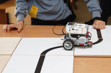 Tekerlekli bloklardan robot inşaatçıları. Siyah bir kasetle araba kullanmak. Yol dedektörüyle kendini kontrol et. Okulda robot laboratuvarı var. Robot konsepti. Fütürist bilimsel konsept. Seçici odak.