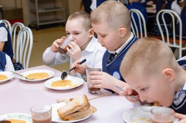Okul çocukları okul kafeteryasında bir masada öğle yemeği yiyorlar. İlköğretim. Seçici odaklanma. Novosibirsk, Rusya, 19.01.2021