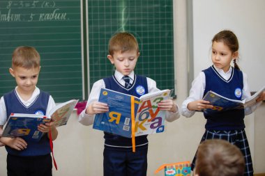 Öğrenciler ders sırasında sınıftaki tahtanın yanında ders kitapları okurlar. İlköğretim. Seçici odaklanma. Rusya, Novosibirsk, 21.01.2021