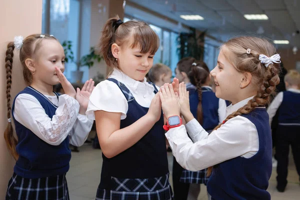 Schoolgirls in uniforms play patty-cake during recess. School primary education. Selective focus.