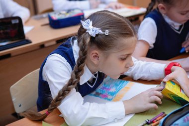 Okul kızları ders sırasında sınıftaki masalarında oturuyorlar. İlköğretim. Seçici odaklanma. Novosibirsk, Rusya, 21.01.2021