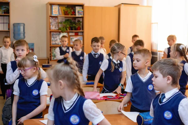 Okul çocukları ders sırasında masalarının arkasında dururlar. İlköğretim. Novosibirsk, Rusya, 19.01.2021