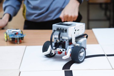 Tekerlekli bloklardan robot inşaatçıları. Siyah bir kasetle araba kullanmak. Yol dedektörüyle kendini kontrol et. Okulda robot laboratuvarı var. Robot konsepti. Fütürist bilimsel konsept. Seçici odak.