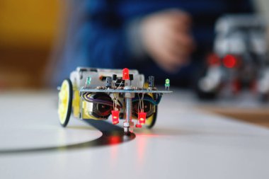 Tekerlekli bloklardan robot inşaatçıları. Siyah bir kasetle araba kullanmak. Yol dedektörüyle kendini kontrol et. Okulda robot laboratuvarı var. Robot konsepti. Fütürist bilimsel konsept. Seçici odak.
