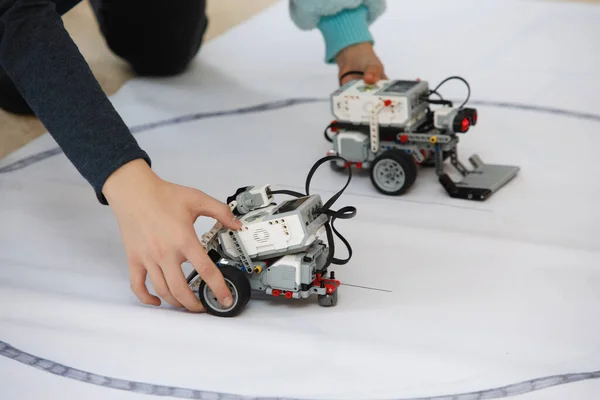 Children\'s hands control of robots from blocks. Robotics laboratory at school. Battle of homemade small robots. Modern technologies. Robotics concept. Futuristic Science Concept. Selective focus.
