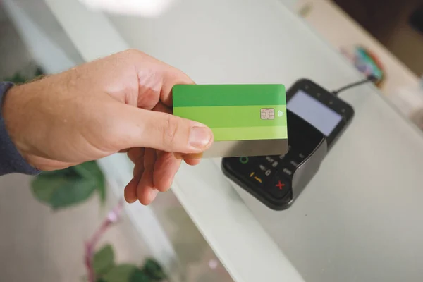 The process of paying with a contactless bank card with a plastic card in the store terminal.