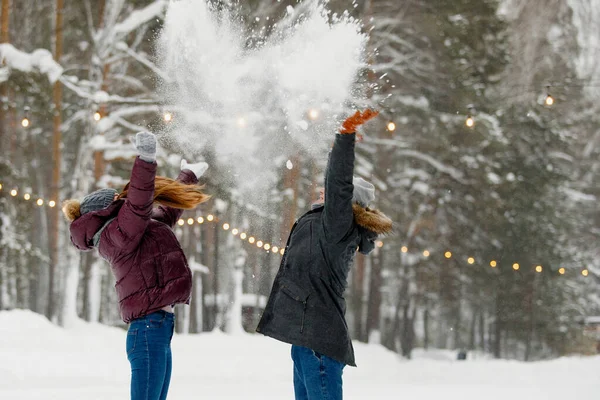 冬服の男と女が公園で雪を投げる フード ニット帽 雪の森のジャケット 健康的なライフスタイル 選択的焦点 — ストック写真